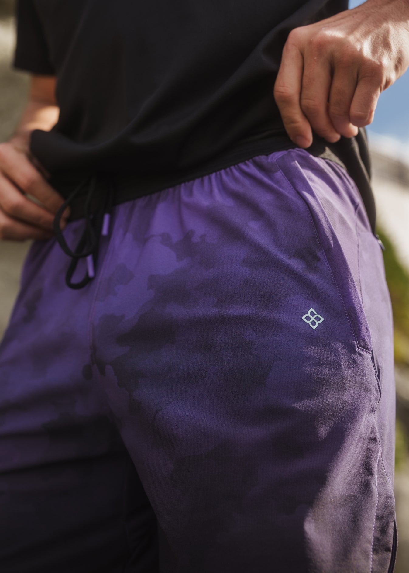 Purple camo active shorts with elastic drawstring waistband and zippered pockets.